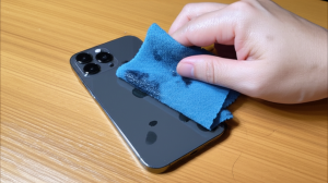 Ilustrasi tangan sedang mengeringkan iPhone 17 Pro Max dengan kain lembut setelah terkena banjir.