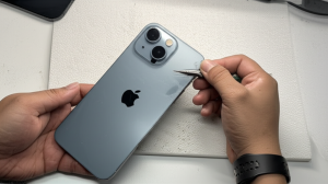 Seorang teknisi sedang memeriksa iPhone 17 Pro Max yang baru saja dibersihkan setelah banjir.