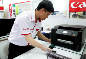 Seorang teknisi sedang memperbaiki printer Canon di service center resmi.