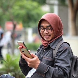 Beberapa orang terlihat gembira memegang handphone dengan notifikasi saldo Gopay bertambah.
