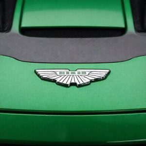 Close-up shot of the Realme GT8 Pro Aston Martin F1 Edition showcasing its British Racing Green color and carbon fiber accents. The Aston Martin logo is prominently displayed.