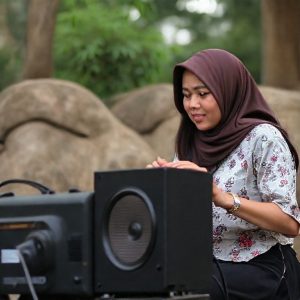 Seorang pria sedang merayu seorang wanita sambil memegang speaker Polytron. Wanita itu tersenyum.