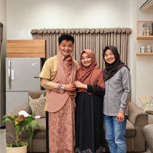 Keluarga bahagia berpose di depan kulkas 436L baru mereka di rumah, menunjukkan kepuasan setelah membeli kulkas impian di Transmart Full Day Sale.